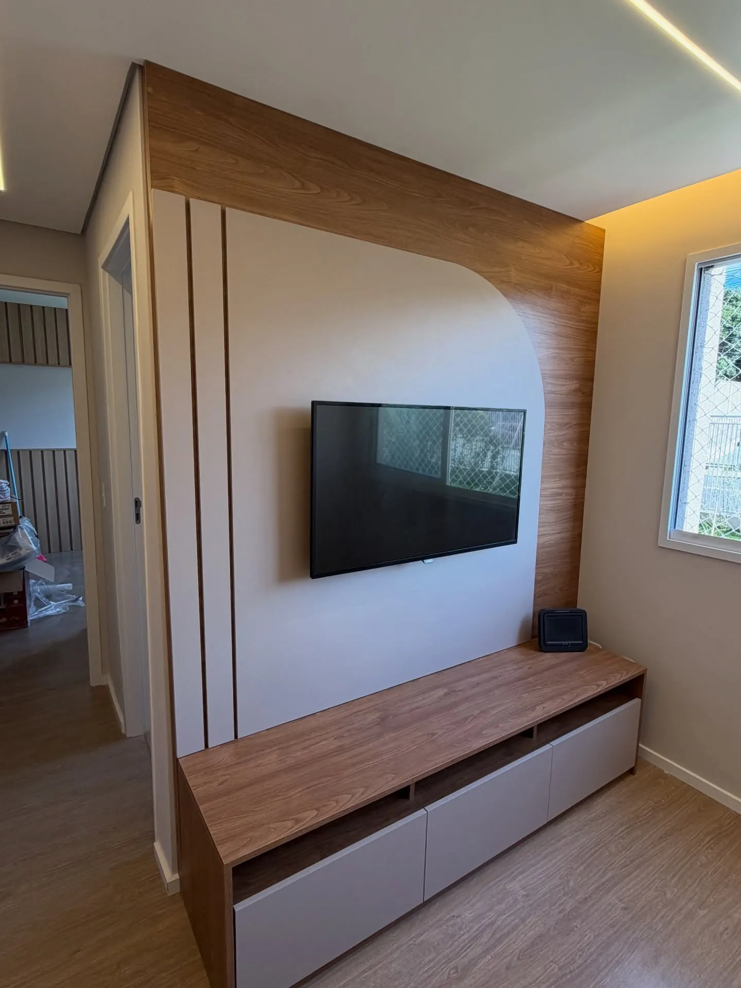 Sala com painel de TV amadeirado e rack suspenso